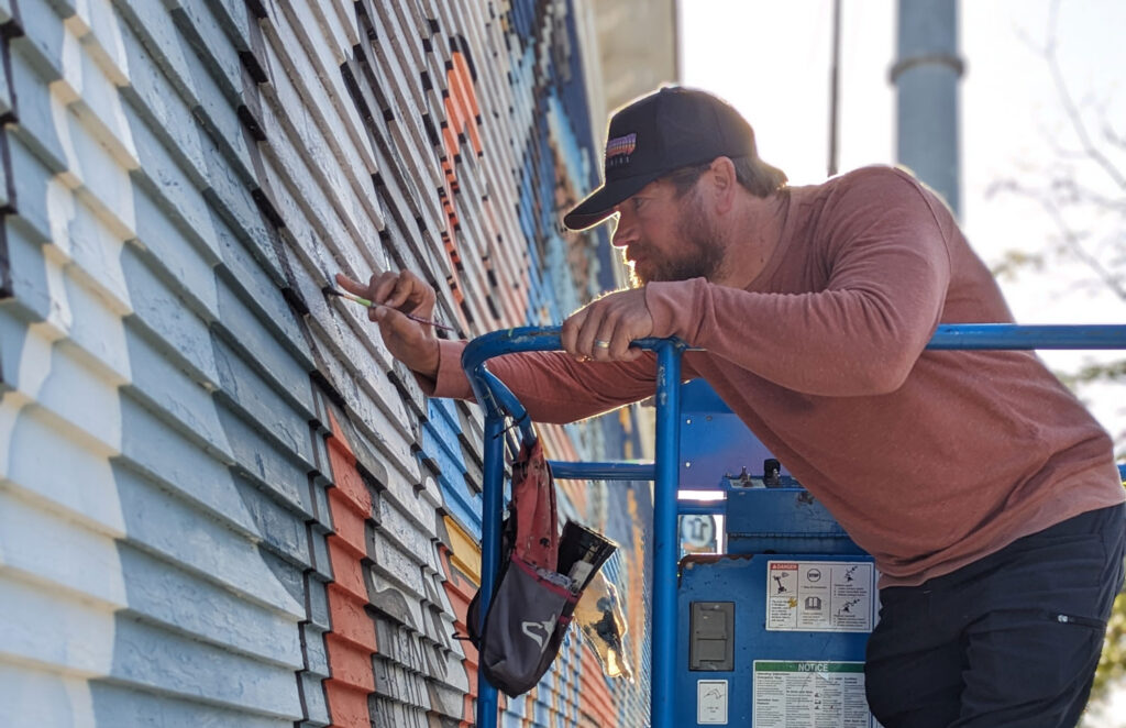 Artist Scott Takes, owner of Underground Art Studios, painting the mural at Sacred Cow Tavern in Cedar Rapids, Iowa.